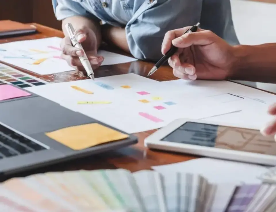 a person holding pens and pen over a paper
