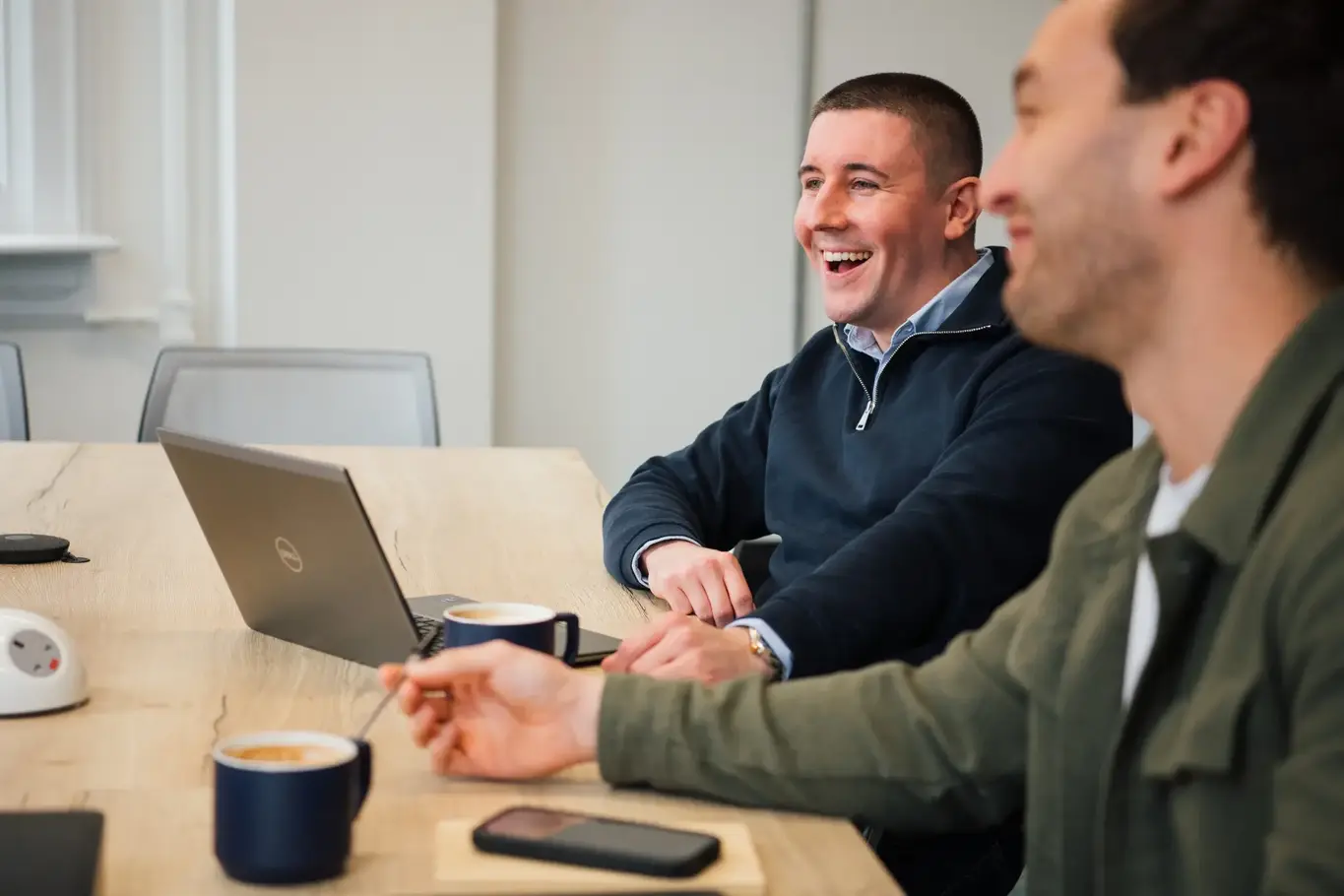 a group of men sitting at a table with coffee and laptop