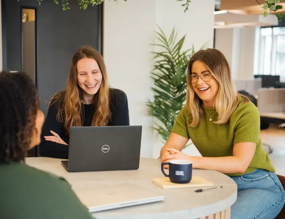 a group of women sitting at a round table with a laptop