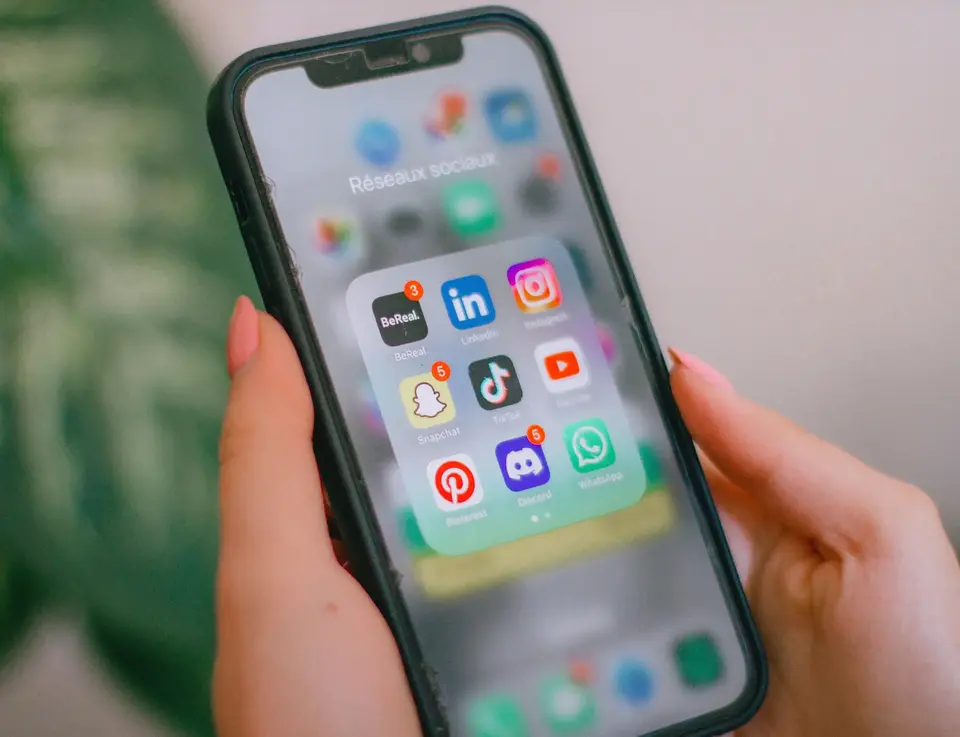 a hand holding a cell phone with icons on the screen