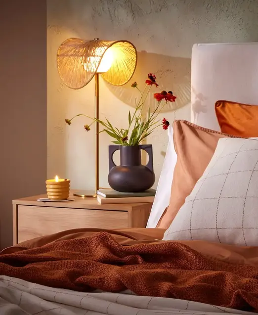 a bed with a lamp and flowers