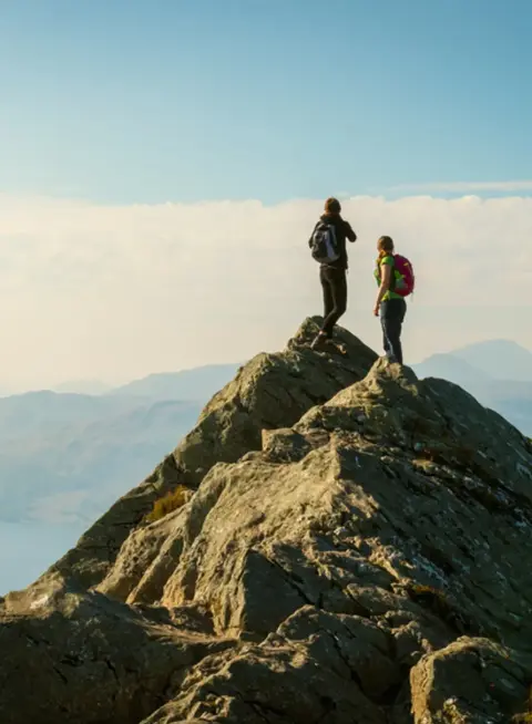 two people standing on a rock