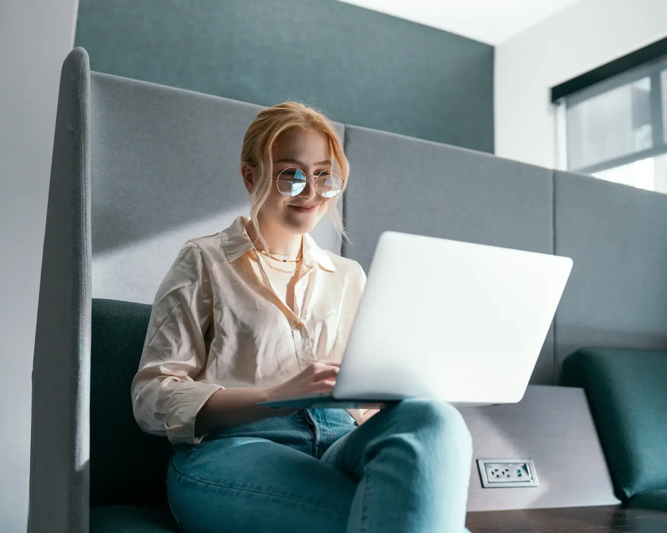 a woman sitting on a bench using a laptop