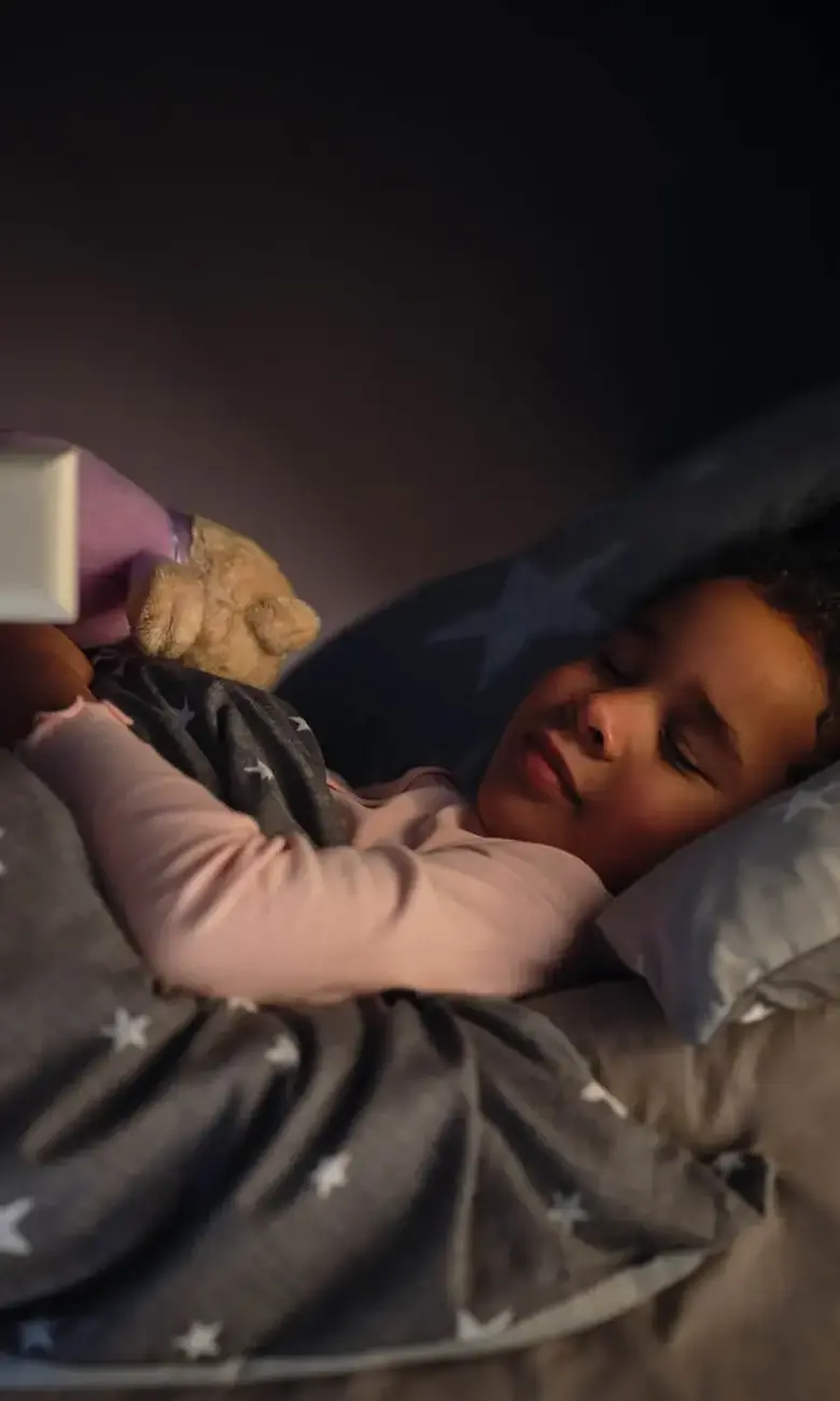 a girl sleeping in bed with a teddy bear