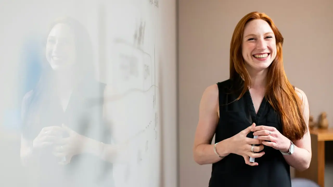 a woman standing next to a whiteboard
