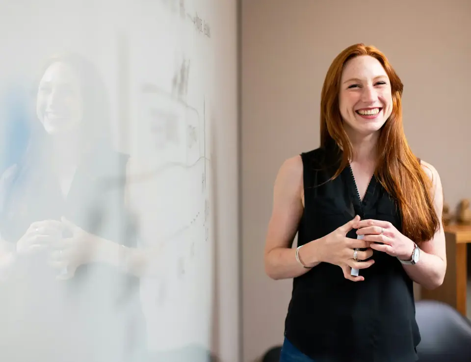 a woman standing next to a whiteboard
