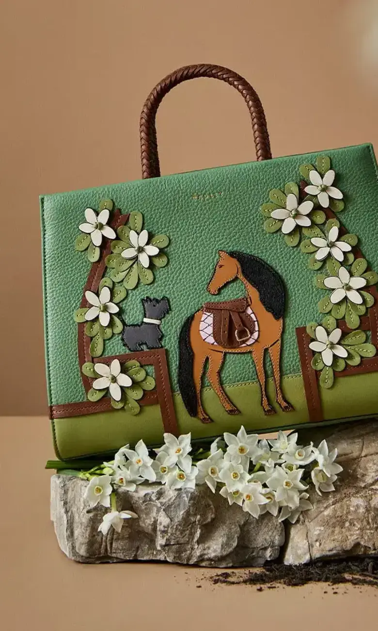 a green bag with a horse and cat on top of a rock