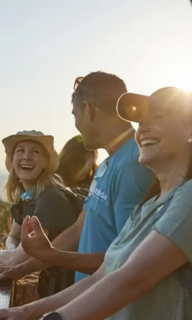 a group of people standing on a ledge looking at a landscape