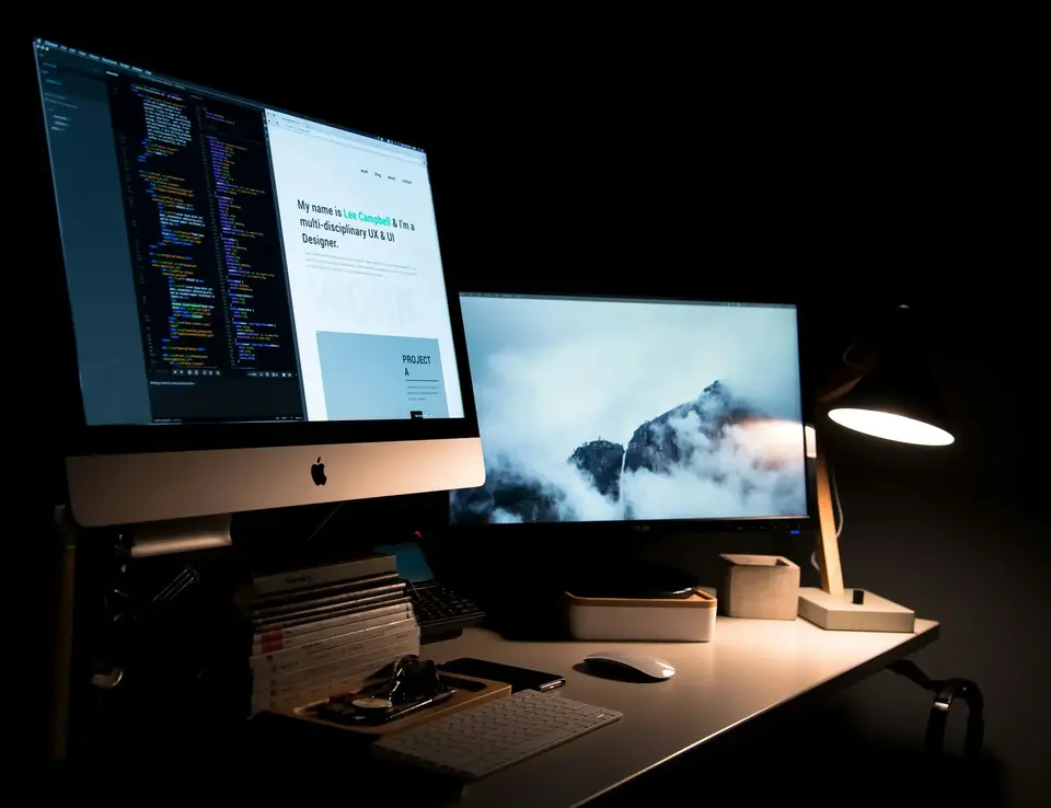 Desktop set up, complete with a big Apple screen, second screen, keyboard and mouse.