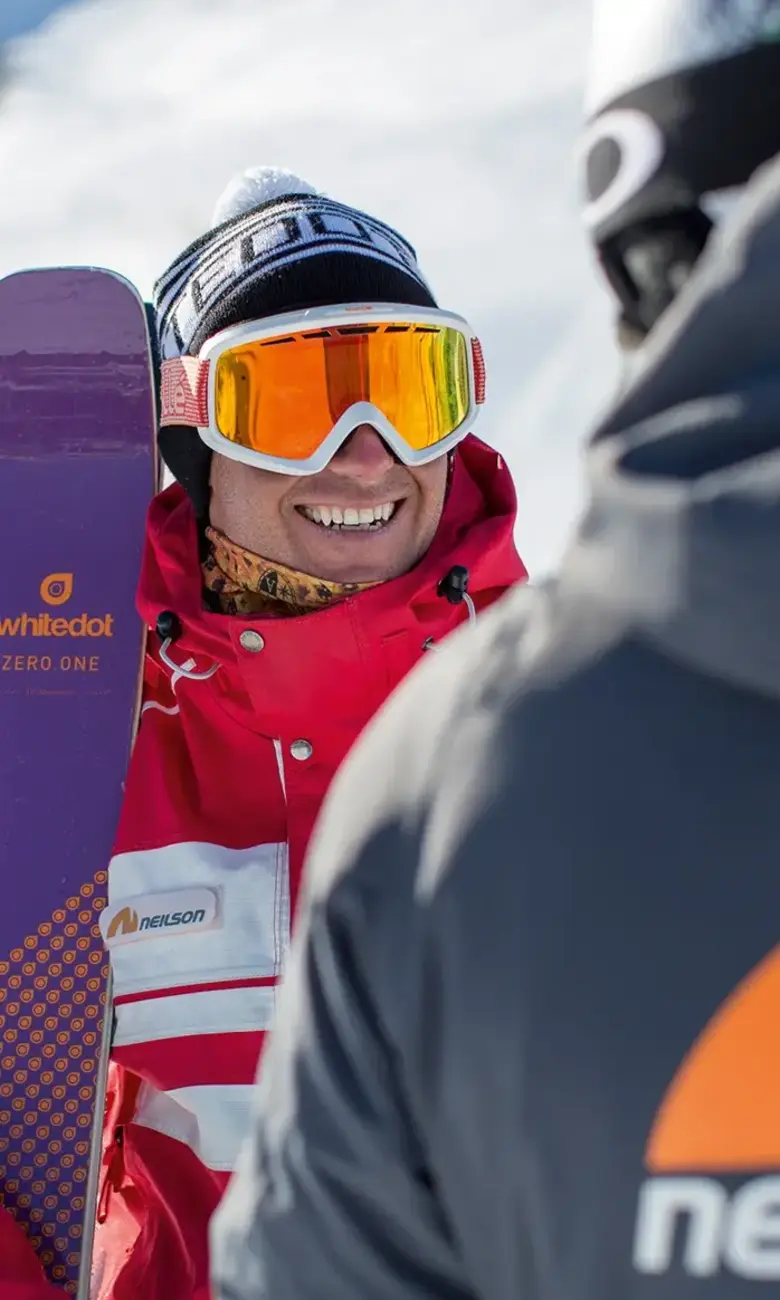 Smiling skier holding a ski up 