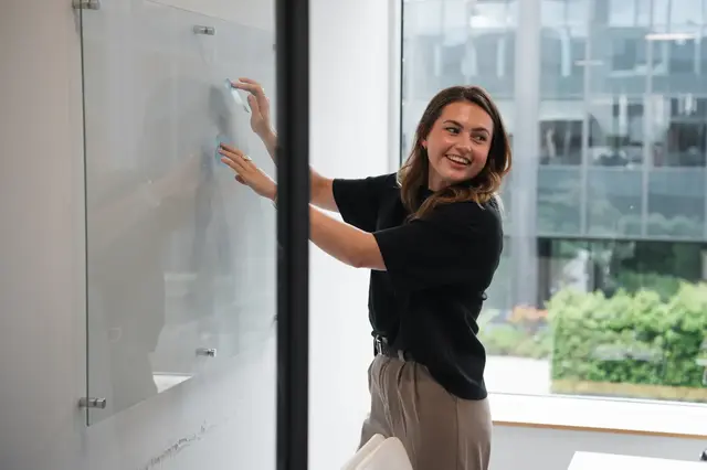 a woman writing on a glass board