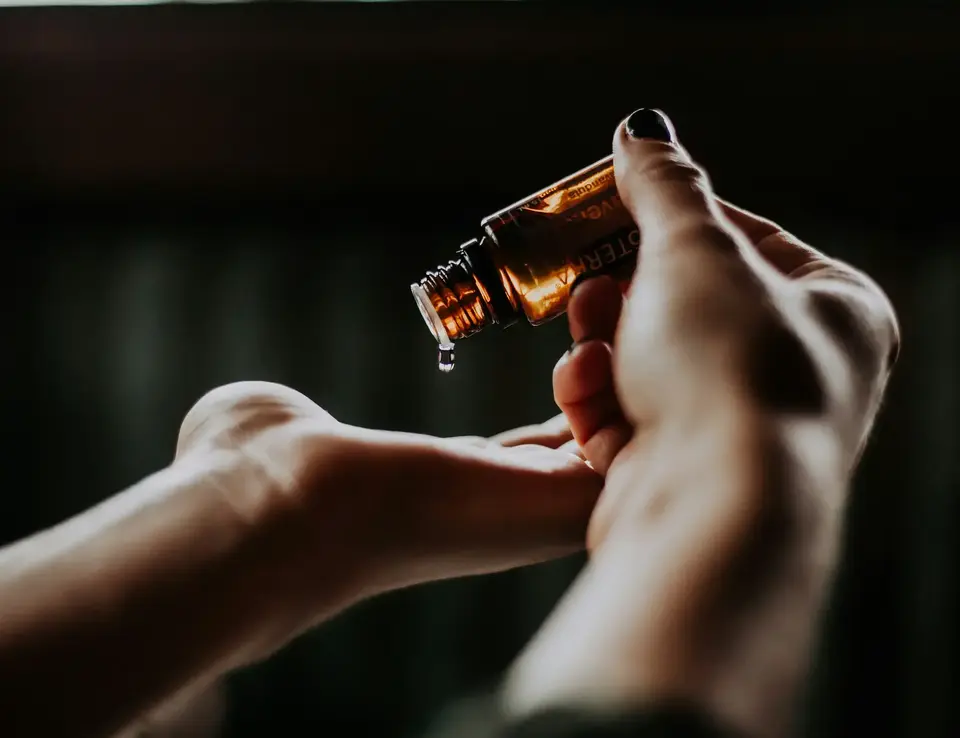 a person pouring a drop of liquid into a hand