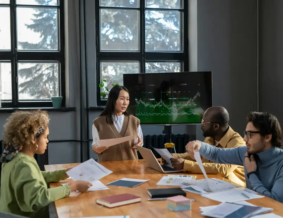 Colleagues sat in a board meeting with a graph on a screen in the background