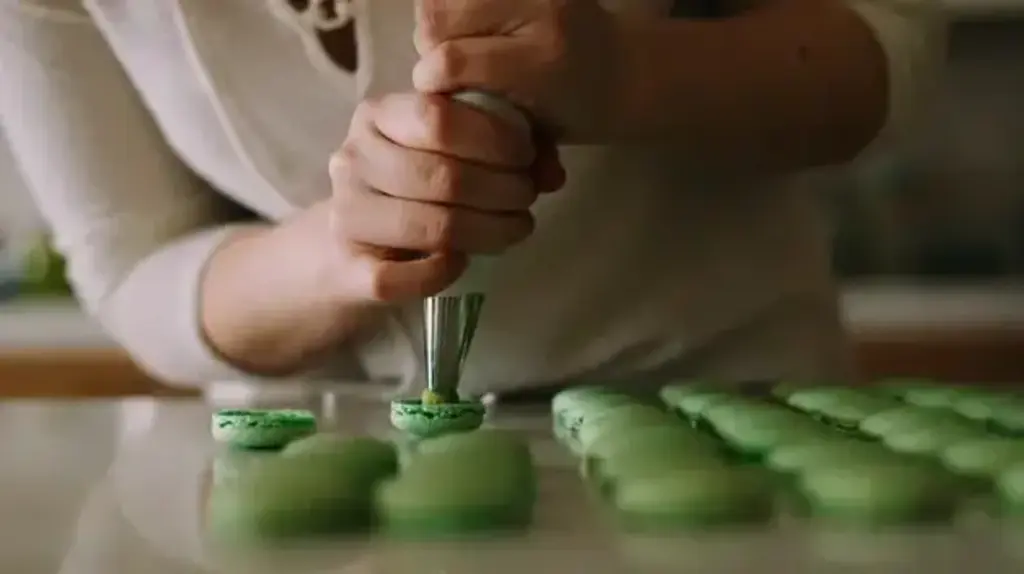 a person using a pastry bag to make macaroons